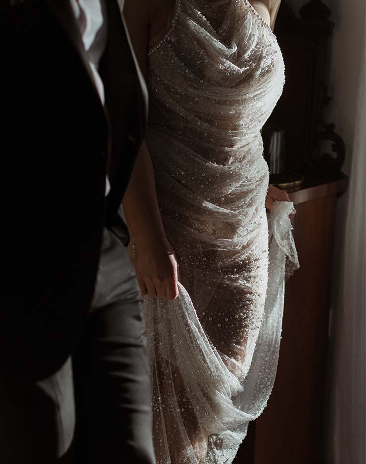 1 - I do I do Gippsland Close-up of a bride in a beaded, draped wedding gown standing beside a man in a dark suit.