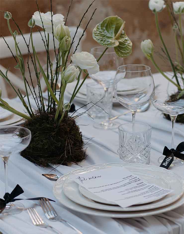 1 - I do I do Gippsland Elegant table setting with white linens, crystal glassware, and a mossy floral centerpiece; printed menu on the plate center stage.