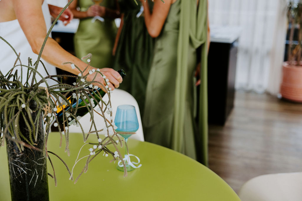 Group of guests around a lime-green table with a blue glass and a decorative plant centerpiece in the foreground.