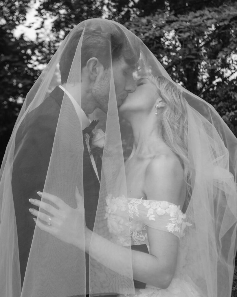 484947640_1066002698882281_8995396734465469662_n - I do I do Gippsland Bride and groom share a kiss under a sheer veil outdoors, black-and-white image.