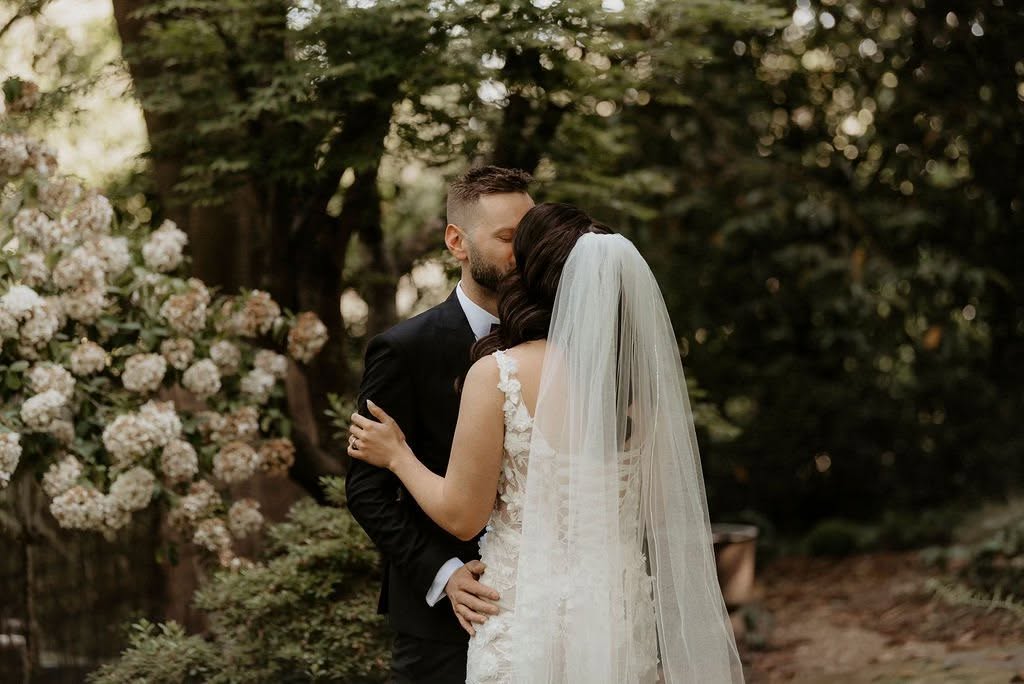 500290963_1119044703578080_5351877789902048339_n - I do I do Gippsland Bride and groom kiss in a garden setting, she in a lace wedding dress with a veil.