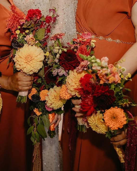 Had to be You Weddings3 - I do I do Gippsland Two people in burnt-orange dresses hold colorful wedding bouquets with peach, orange, and red flowers.