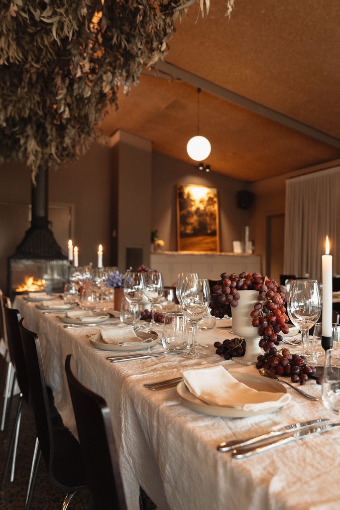 CarrajungEstate_Preview_2026-039 | I do I do Gippsland Long dining table set for a formal dinner with candles, glassware, and grape centerpieces in warm lighting