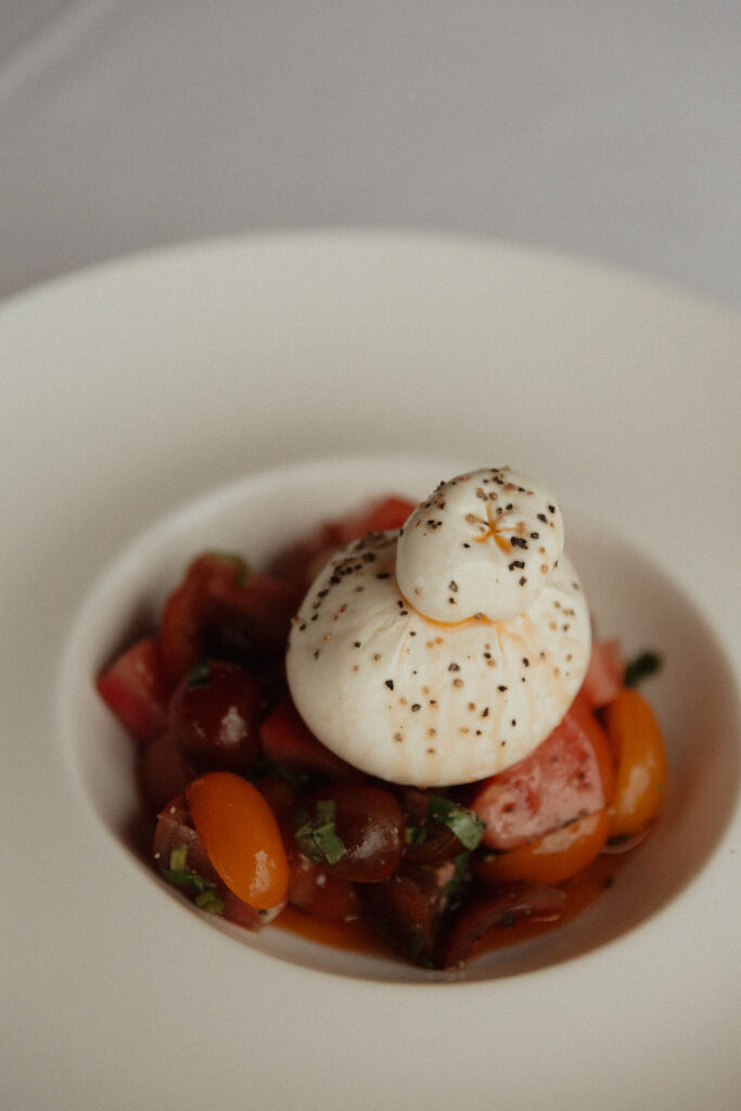 CarrajungEstate_Preview_2026-238 | I do I do Gippsland Two small white burrata balls dusted with spices sit atop a chopped tomato and bell pepper salad in a white bowl.